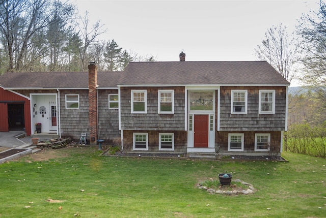 split foyer home with a shingled roof, a front lawn, and a chimney