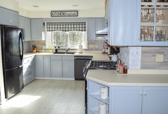 kitchen featuring a sink, light countertops, freestanding refrigerator, decorative backsplash, and dishwashing machine