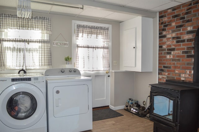 laundry room featuring separate washer and dryer, baseboards, a wood stove, and cabinet space
