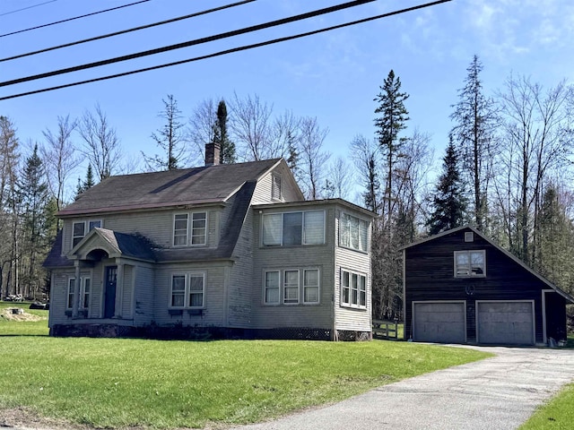 view of front of house featuring an outdoor structure, a chimney, a front yard, and a detached garage