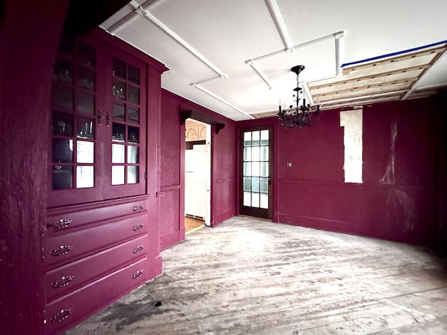 unfurnished dining area featuring a chandelier and wood finished floors