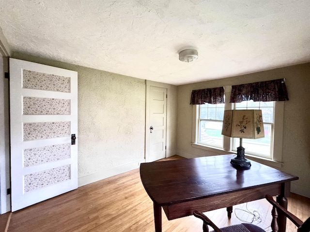 home office featuring light wood finished floors, a textured ceiling, and baseboards