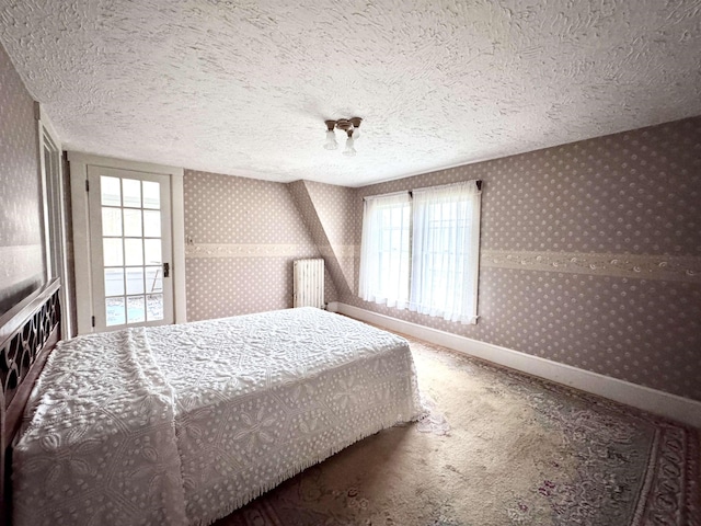 carpeted bedroom with baseboards, radiator heating unit, wallpapered walls, and a textured ceiling