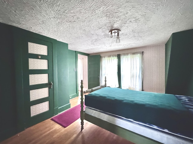 bedroom featuring a textured ceiling, wood finished floors, and an accent wall