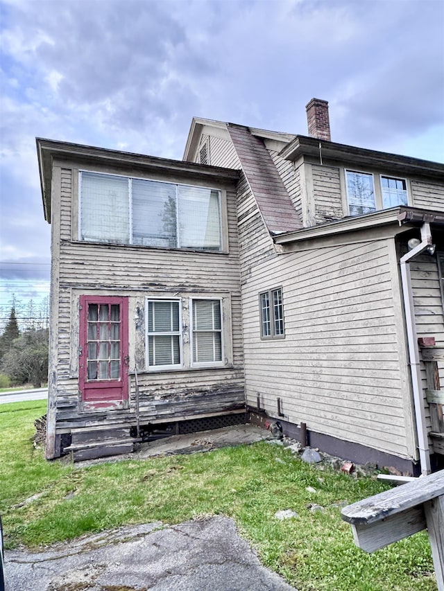 rear view of house with a chimney and a lawn