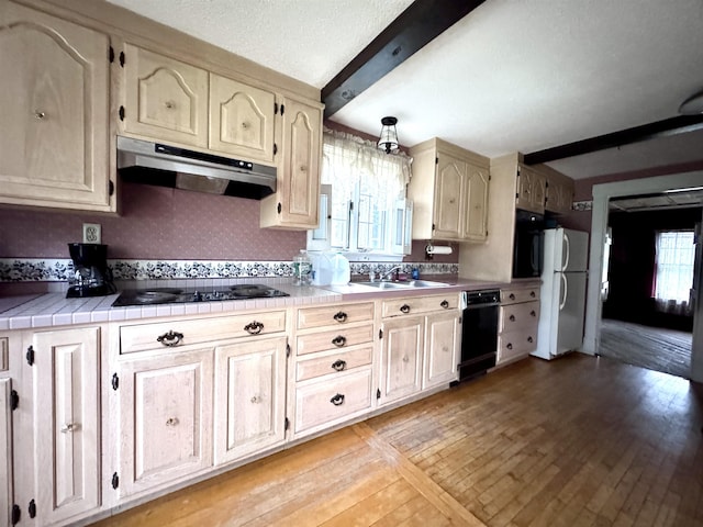 kitchen featuring a sink, beam ceiling, black appliances, under cabinet range hood, and light wood-style floors