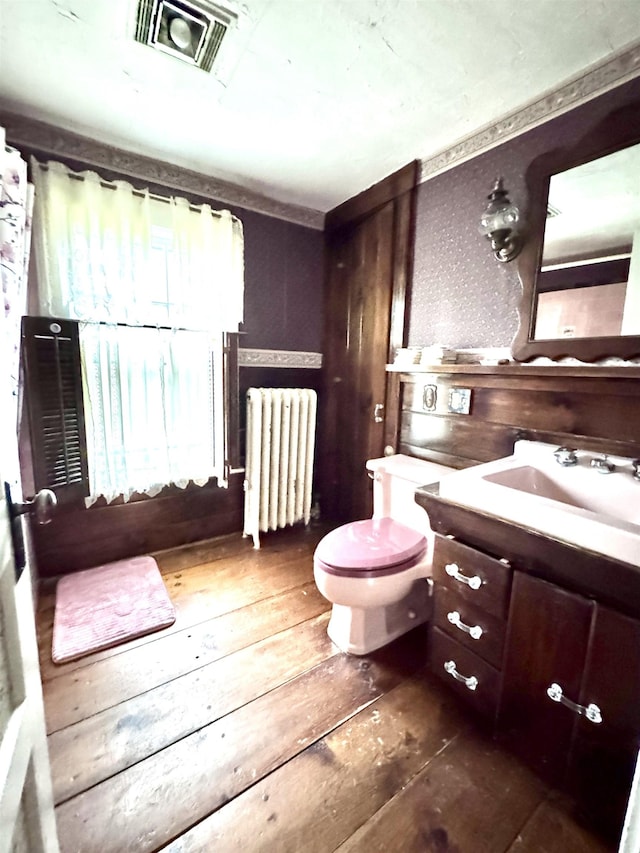 bathroom featuring toilet, radiator, visible vents, vanity, and hardwood / wood-style flooring