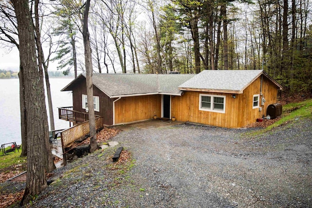 view of front facade featuring a shingled roof, central air condition unit, and gravel driveway