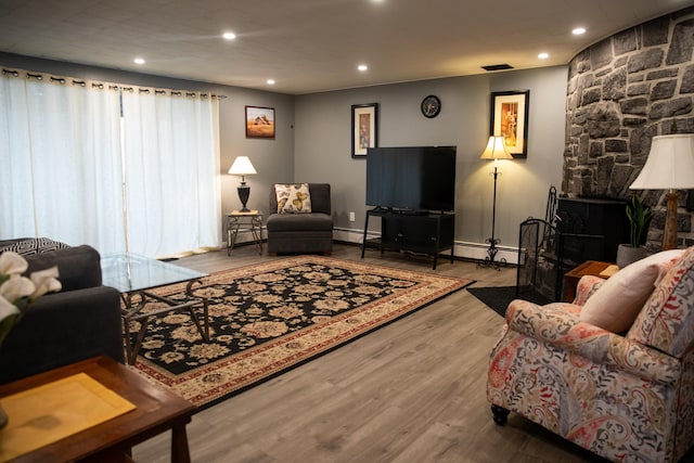 living area with recessed lighting, a baseboard radiator, a baseboard heating unit, and wood finished floors