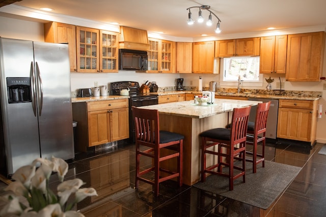 kitchen with glass insert cabinets, a kitchen bar, light stone counters, a sink, and black appliances
