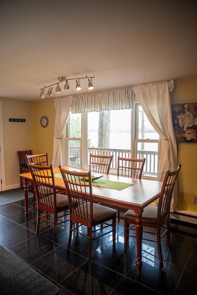 dining space with baseboards, granite finish floor, and rail lighting