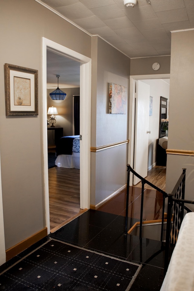 hall featuring baseboards, ornamental molding, and an upstairs landing