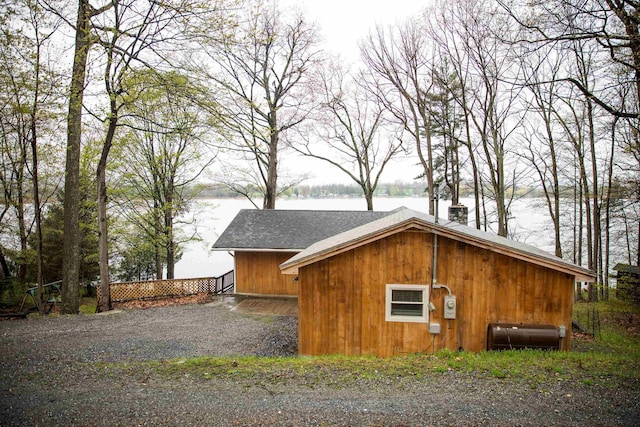view of side of property with a shingled roof and a water view