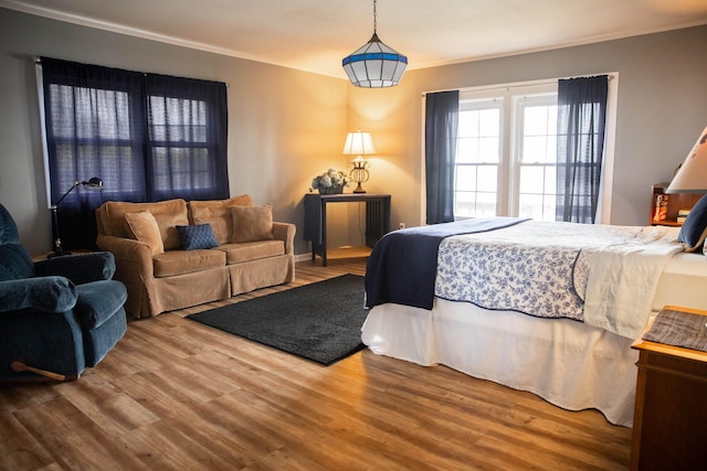 bedroom with ornamental molding and wood finished floors