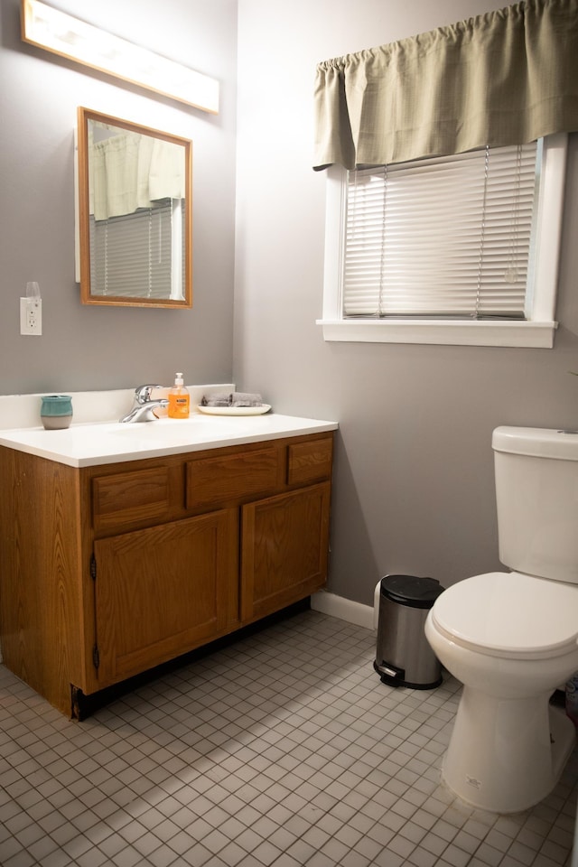 half bathroom with toilet, baseboards, tile patterned floors, and vanity