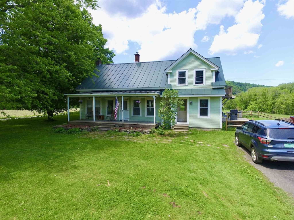 1907 River Rd, Moretown, VT 05602 - view of front facade featuring a porch, a front yard, a chimney, a standing seam roof, and metal roof