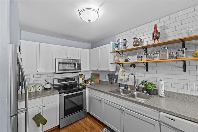 kitchen with a sink, appliances with stainless steel finishes, decorative backsplash, and white cabinets