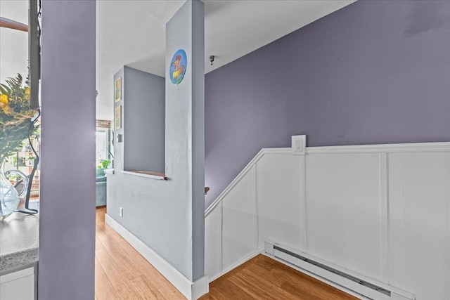 staircase with wood finished floors and baseboard heating