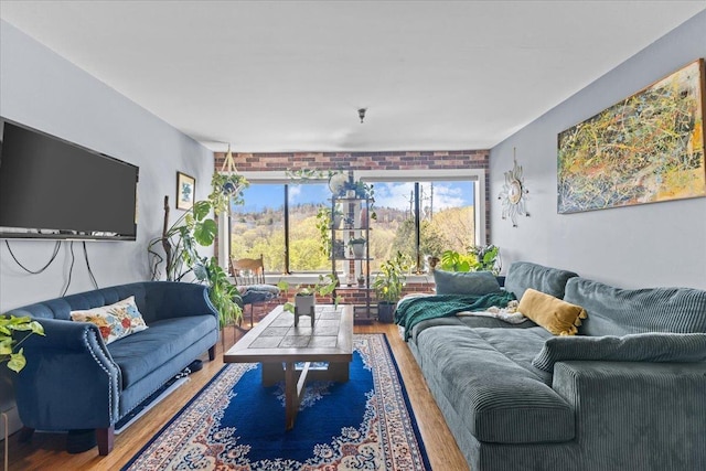 living room featuring brick wall and wood finished floors