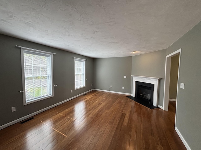 unfurnished living room featuring a fireplace, baseboards, visible vents, and dark wood-type flooring