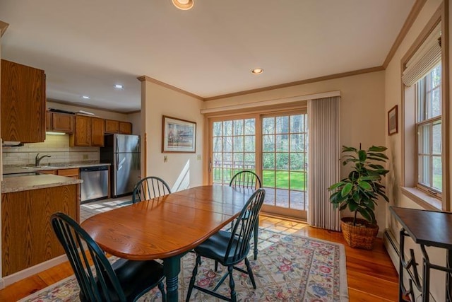 dining space featuring crown molding, plenty of natural light, and light wood finished floors