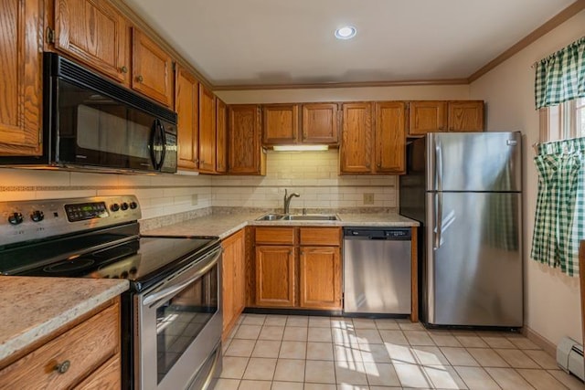 kitchen with brown cabinets, appliances with stainless steel finishes, a sink, and light countertops