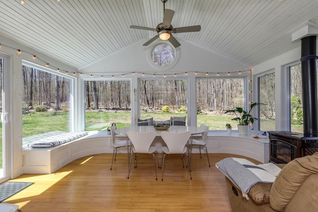 sunroom / solarium featuring lofted ceiling, wooden ceiling, wood finished floors, and a wood stove