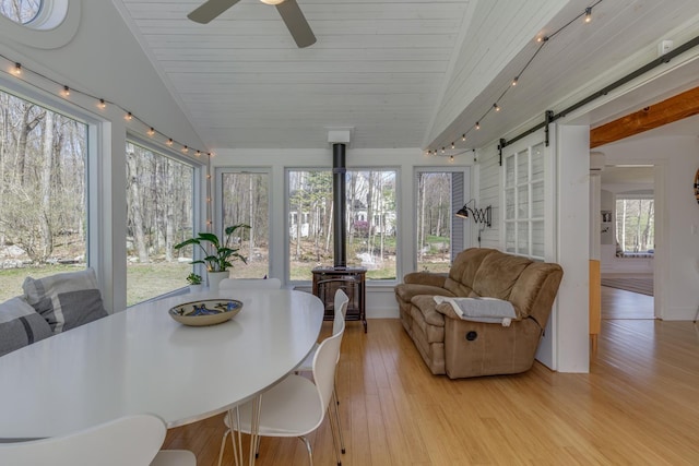 sunroom featuring a barn door, lofted ceiling, wood finished floors, and a wealth of natural light