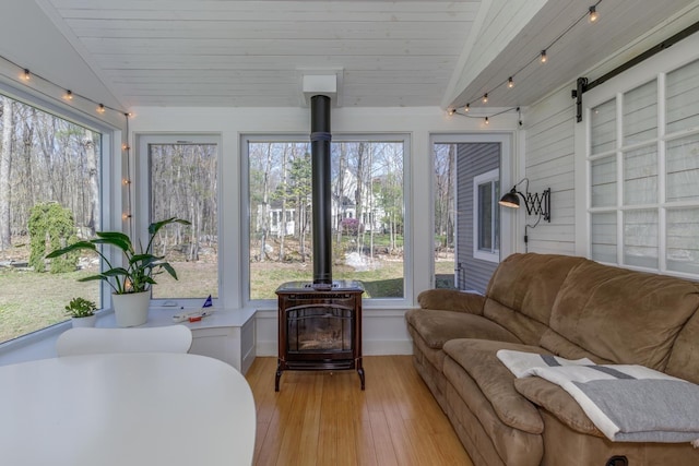 sunroom / solarium with hardwood / wood-style flooring, plenty of natural light, and a wood stove