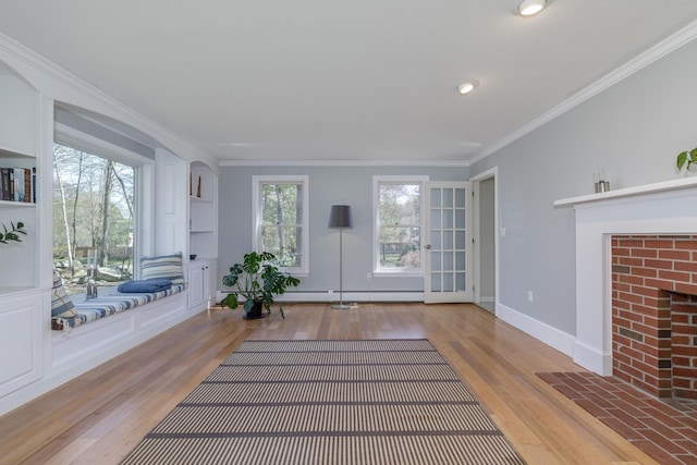 interior space with ornamental molding, a brick fireplace, wood finished floors, and baseboard heating
