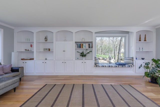 sitting room featuring built in features, ornamental molding, and light wood-style floors