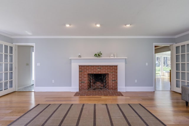 unfurnished living room with a fireplace with flush hearth, baseboards, ornamental molding, and wood finished floors