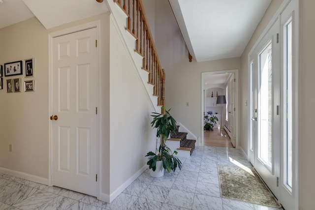 foyer featuring stairs, baseboards, a wealth of natural light, and marble finish floor