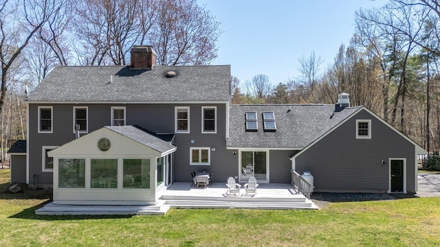 back of property with a yard, a chimney, a sunroom, and a deck