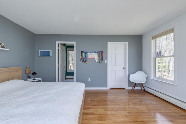 bedroom featuring baseboards, baseboard heating, and light wood-type flooring