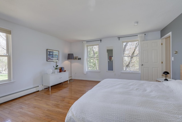 bedroom featuring baseboards, baseboard heating, and light wood finished floors