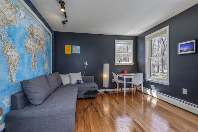 living area with track lighting, baseboards, a baseboard radiator, and hardwood / wood-style flooring