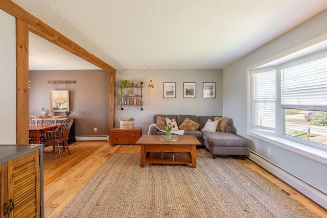 living area with light wood-style flooring, a textured ceiling, baseboards, baseboard heating, and a baseboard radiator