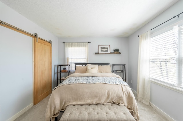 bedroom with light colored carpet, a barn door, and baseboards