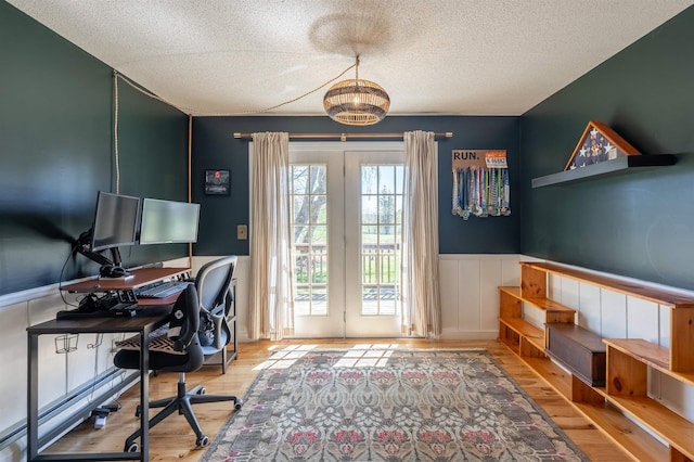 office space with a chandelier, a textured ceiling, a wainscoted wall, and wood finished floors