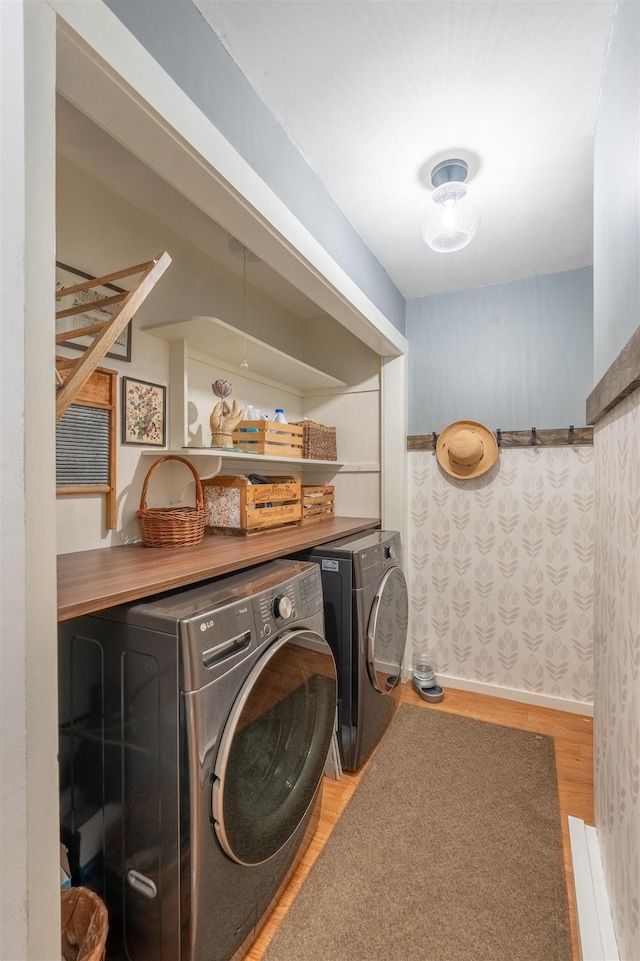 clothes washing area with washing machine and clothes dryer, baseboards, laundry area, and wood finished floors