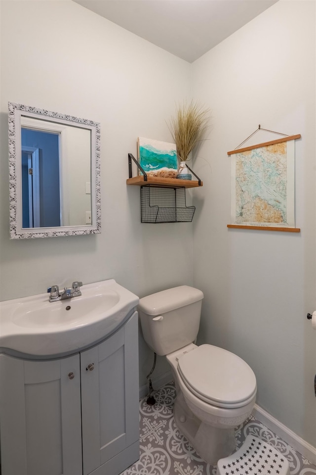 half bath featuring baseboards, tile patterned floors, vanity, and toilet