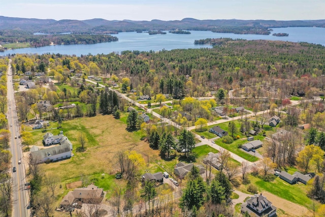 drone / aerial view with a water and mountain view and a wooded view