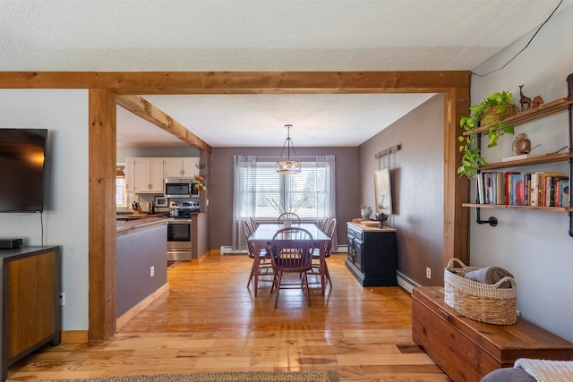 dining space featuring a textured ceiling, beamed ceiling, light wood finished floors, and plenty of natural light