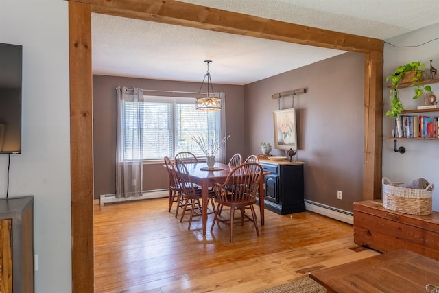 dining room featuring an inviting chandelier, baseboards, light wood-style flooring, and a baseboard radiator