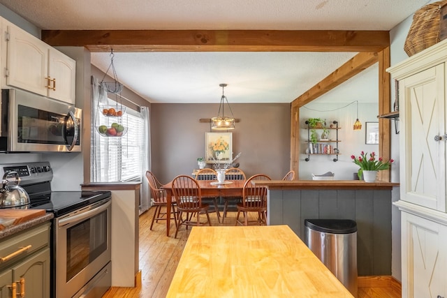 kitchen with stainless steel appliances, wood counters, pendant lighting, light wood finished floors, and beamed ceiling