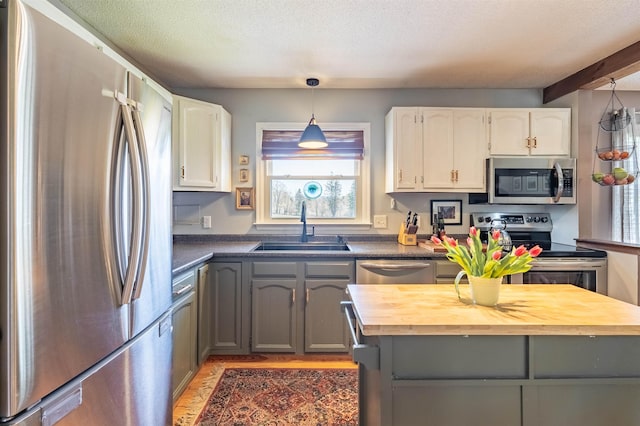 kitchen featuring butcher block counters, a sink, stainless steel appliances, white cabinets, and gray cabinets