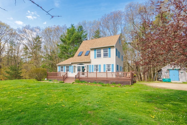 view of front of property with a front yard, roof with shingles, and a wooden deck
