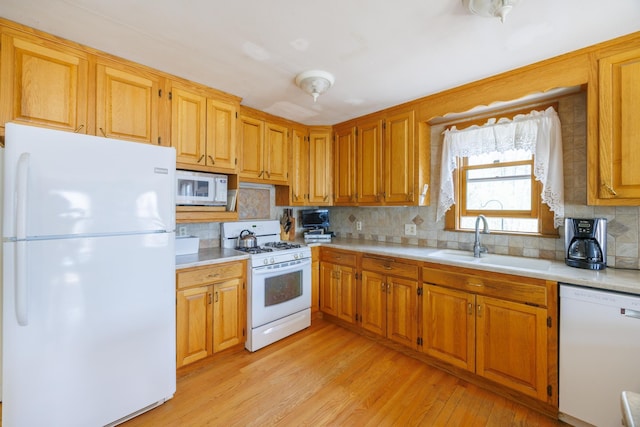 kitchen featuring white appliances, light countertops, light wood-style flooring, and a sink