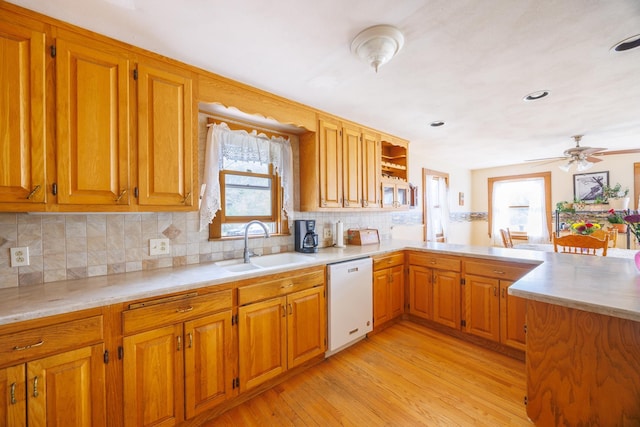 kitchen featuring a sink, brown cabinetry, light wood-style flooring, light countertops, and white dishwasher